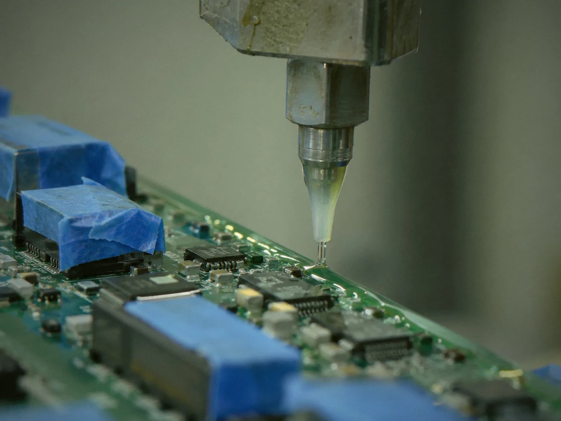 Coating nozzle over a circuit board with masked connectors