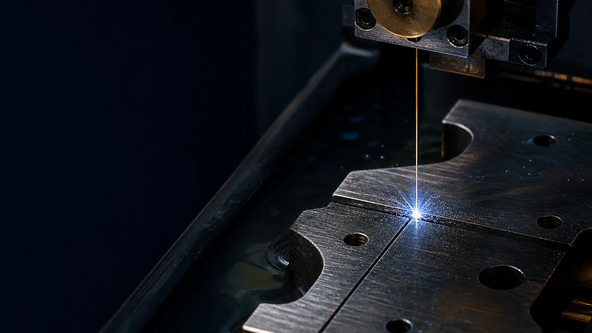 Wire EDM cutting a hardened steel die plate submerged in dielectric fluid