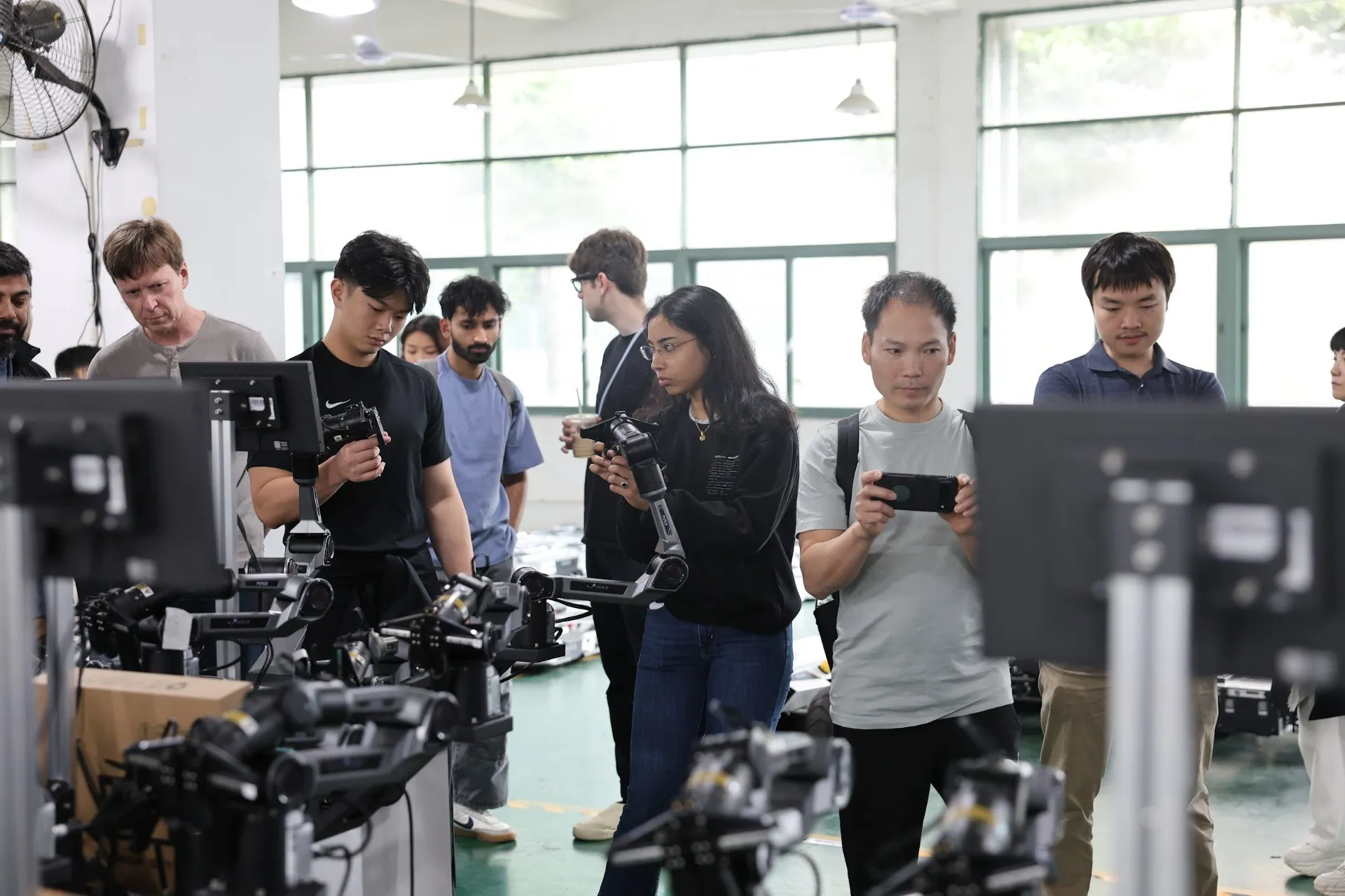 Hardware founders watching teleoperated robot arms during a visit to a Shenzhen robotics lab