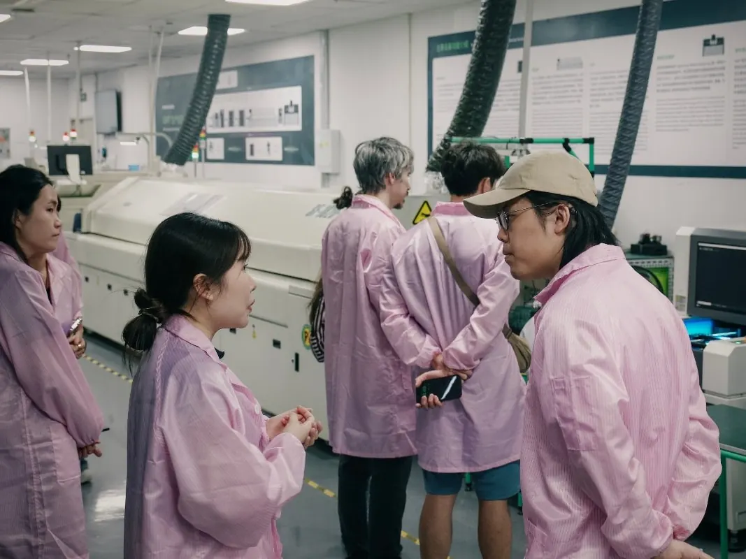 Founders in ESD smocks walking a PCB assembly line in Shenzhen
